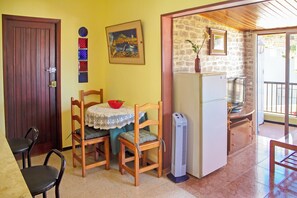 Ein Zimmer mit Holztür, Tisch mit Stühlen, Kühlschrank und Wand mit Gemälde und Vase.