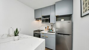 A modern kitchen with grey cabinets, a stainless steel refrigerator, a built-in microwave, and a gas stove. - Arbor Flats #4 in the Heart of Houston (Houston)