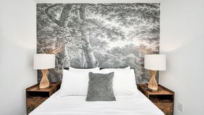 A bedroom with a large bed, two nightstands, a wall tapestry, and two lamps. - Arbor Flats #4 in the Heart of Houston (Houston)