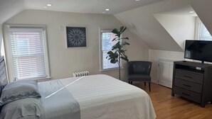 Ein Schlafzimmer mit Bett, Sessel, Fernseher und Heizkörper.