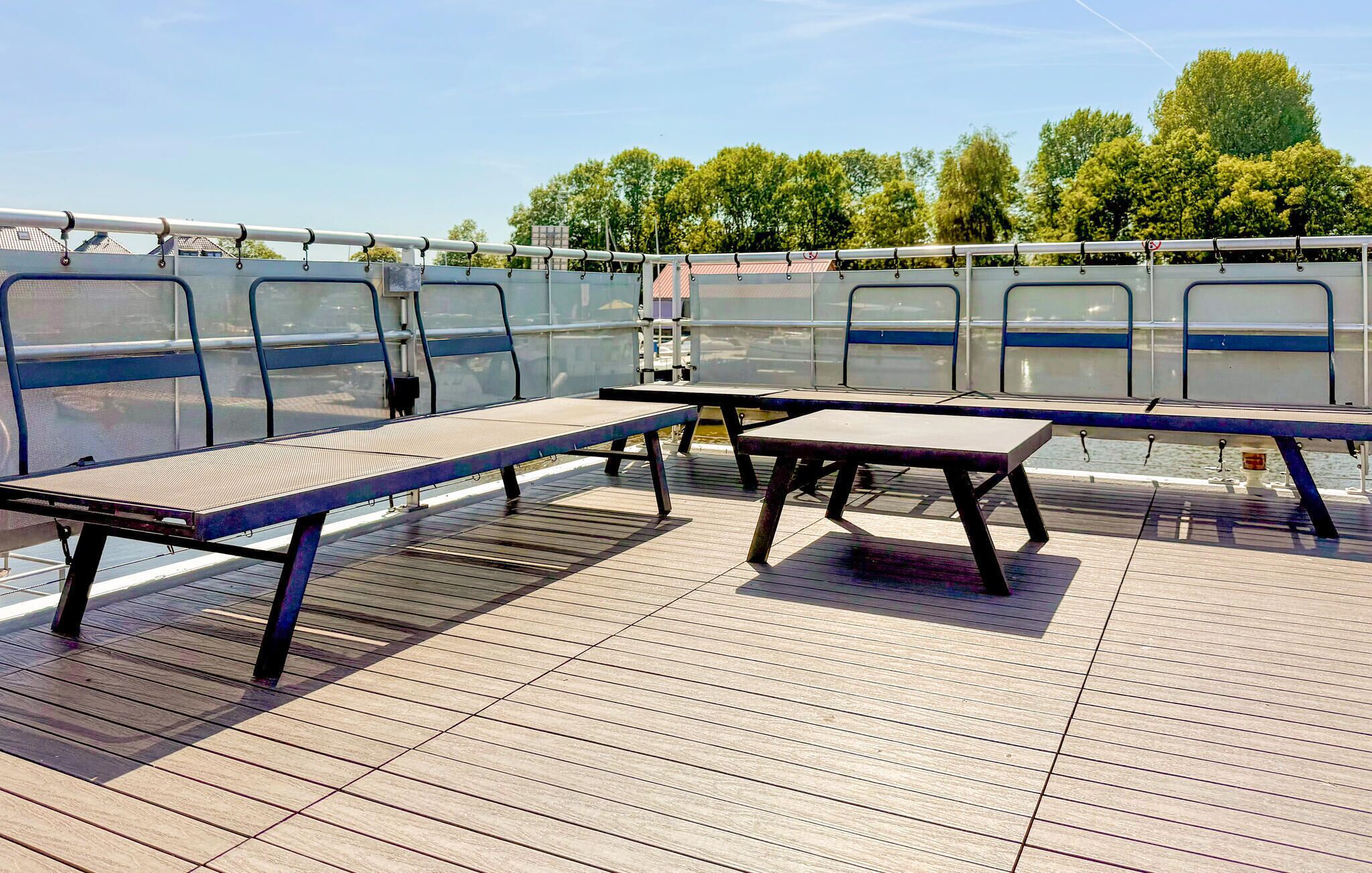 An outdoor deck with picnic tables and a view of a river and trees.