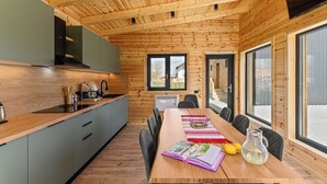 A modern kitchen with wooden walls and a dining area with a table and chairs.