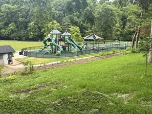 A playground with green slides and a small building, surrounded by grass and trees. - Quiet Inn Stay with a Kentucky Country Feel (Versailles)