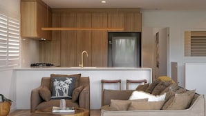 A compact living space with a kitchenette, seating area, and a window with blinds. - Ocean views: Steps from Sunrise Beach (Noosa)