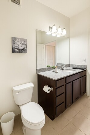 A bathroom with a toilet, a sink, a mirror, and a picture on the wall. - Family & Group Retreat|3 Queens Beds Pool Table 11 (Birmingham)