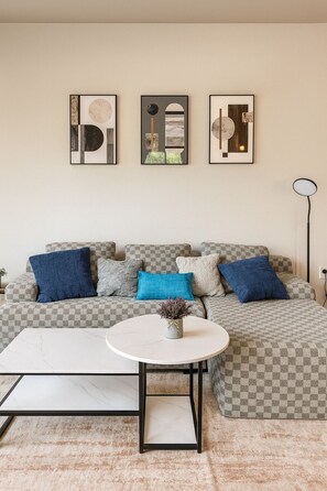 A living room with a sofa, a round coffee table, and three framed artworks on the wall. - Family & Group Retreat|3 Queens Beds Pool Table 11 (Birmingham)
