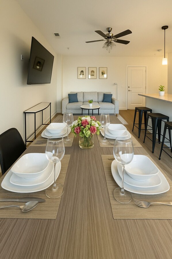 A dining area with a long table set for six, a ceiling fan, a sofa, and a small plant. - Family & Group Retreat|3 Queens Beds Pool Table 11 (Birmingham)