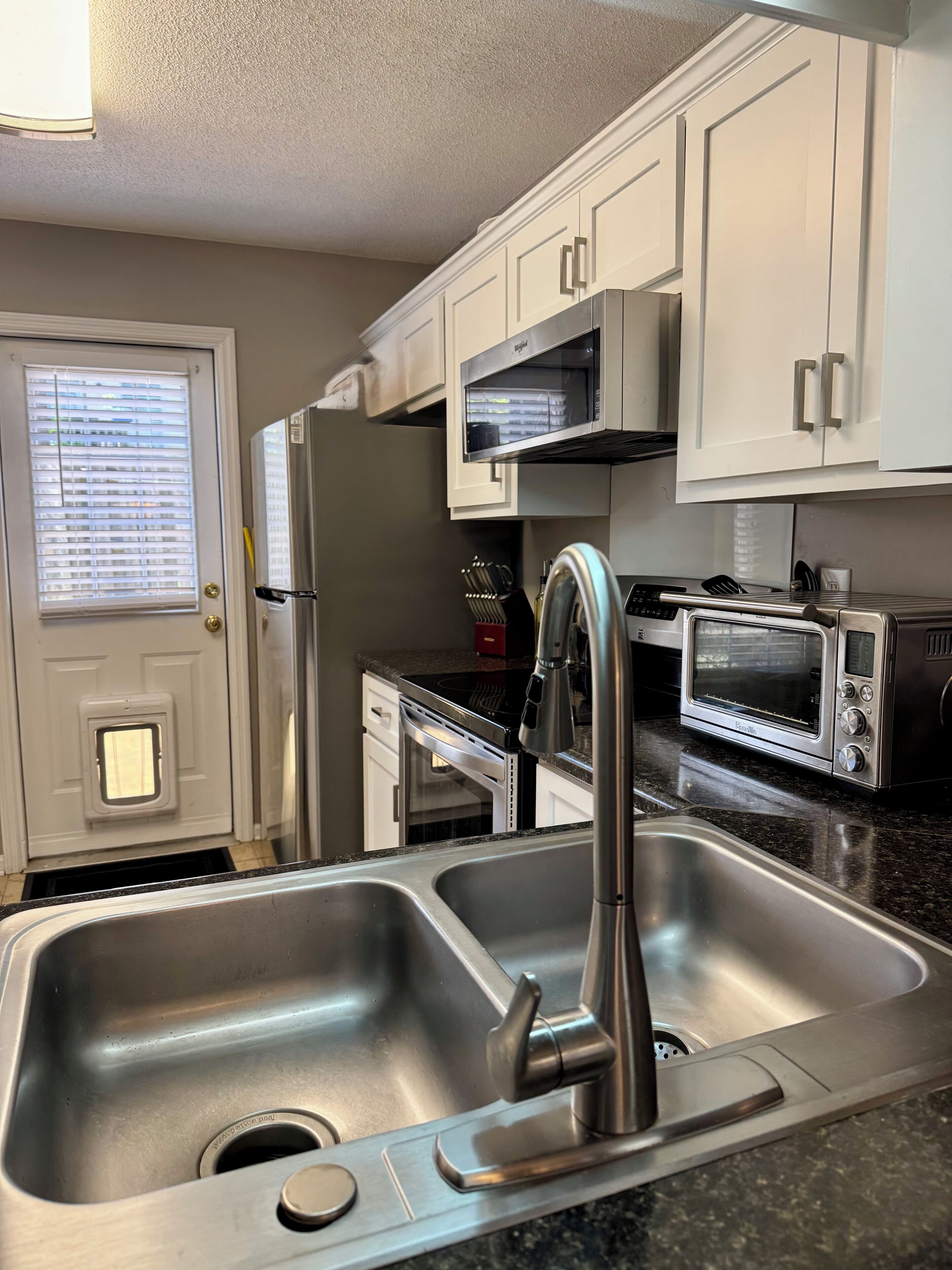 A kitchen with a stainless steel sink, a microwave, and a toaster oven.