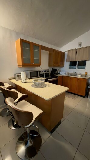Une cuisine avec des meubles de rangement en bois, un îlot central, un four à micro-ondes, un grille-pain et un évier.