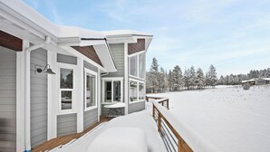Ein Haus mit überdachter Veranda, einer Bank und Blick auf eine verschneite Landschaft.