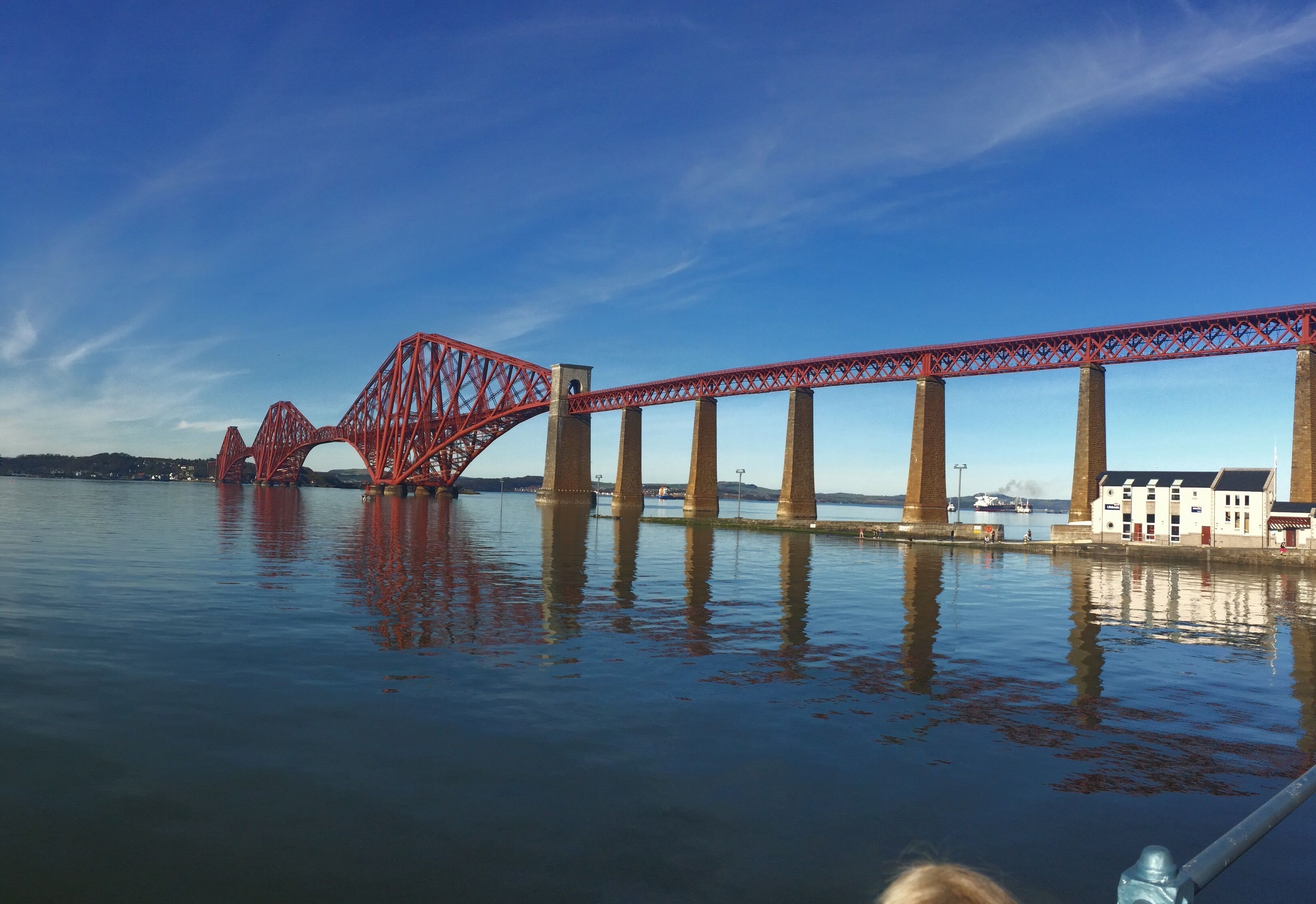 A red bridge over water with buildings on the right.