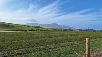 A rural landscape with rolling hills, a clear sky, and distant mountains.