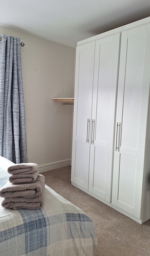 A bedroom with a bed, a white wardrobe, a hanging light, and a window with curtains.