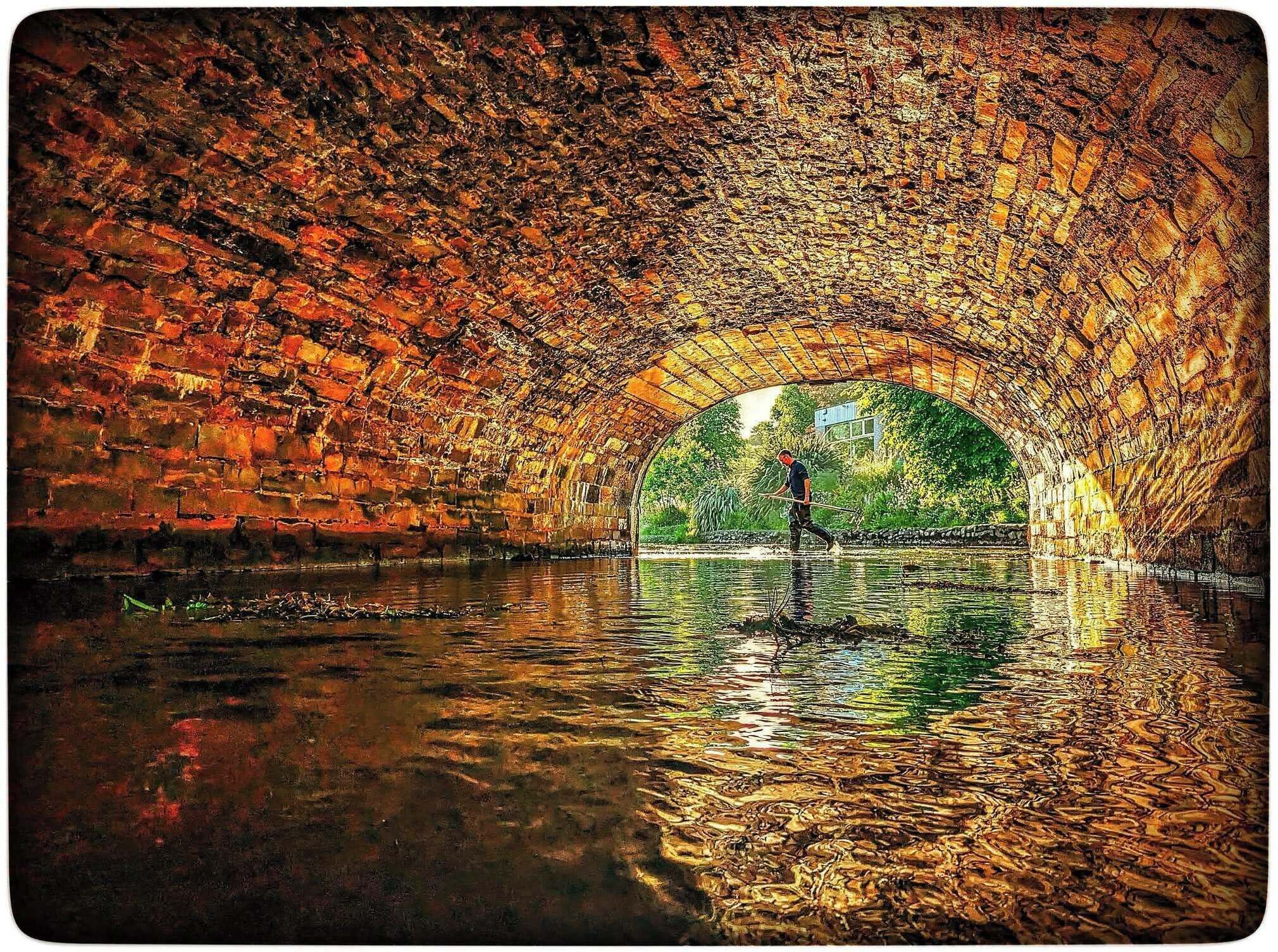 A stone tunnel with a person walking through it.
