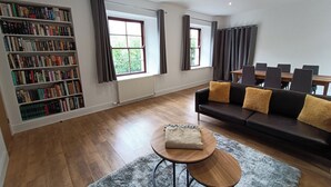Un salon moderne comprenant un canapé, une table basse, une bibliothèque et un coin repas avec des chaises.