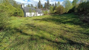 Un champ verdoyant avec un bâtiment blanc et des arbres en arrière-plan.