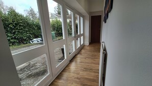 Un couloir doté de grandes fenêtres, d’un plancher en bois et d’un radiateur.