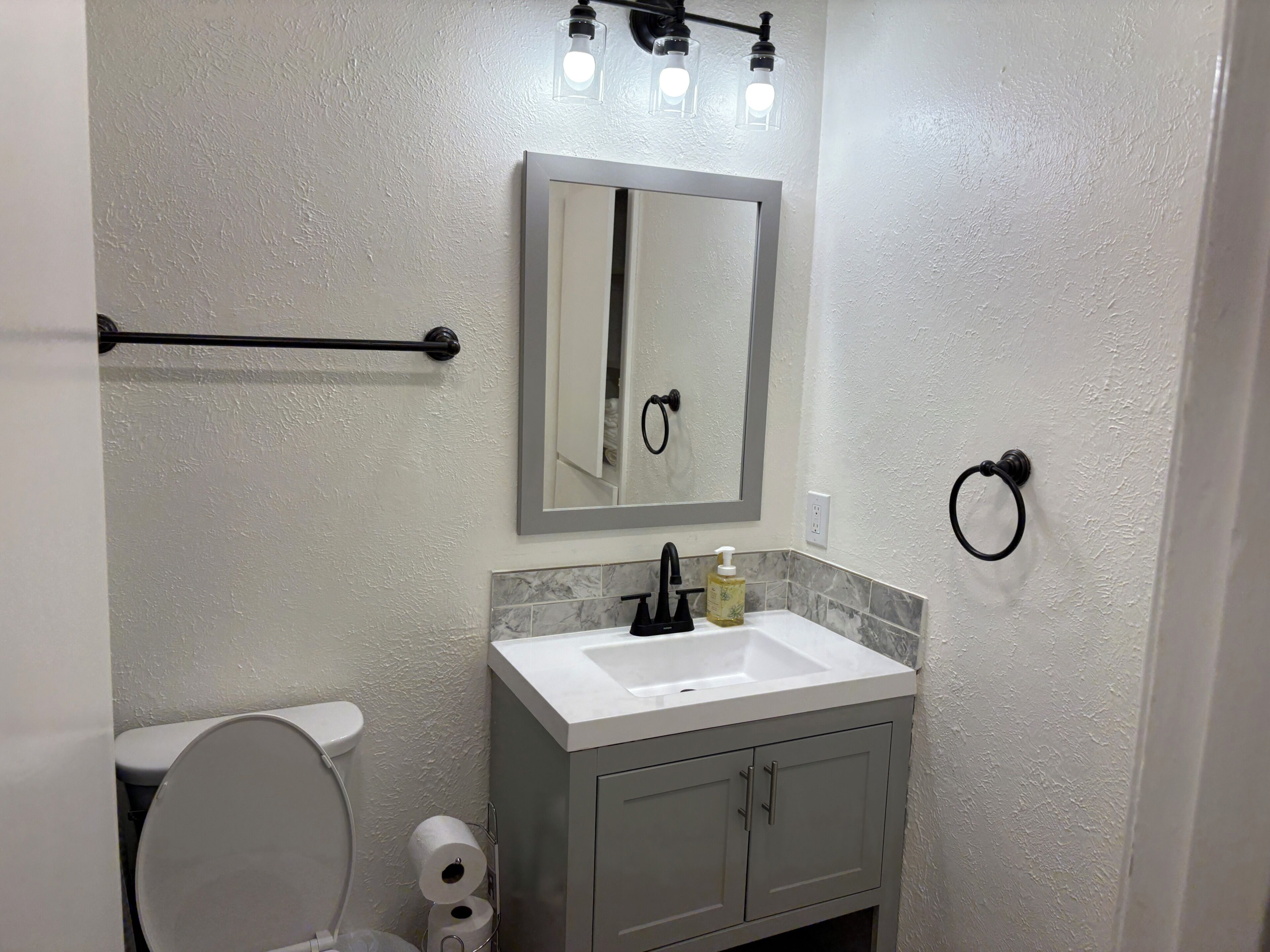 Ein Badezimmer mit Toilette, Waschbecken, Spiegel und Handtuchhalter.