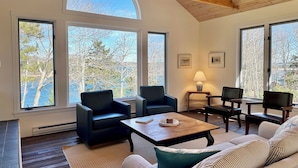 A spacious living room with large windows, a wooden ceiling, and a cozy seating area. - Oceanfront Escape on Lish’s Cove – Private Dock & Sunrise Views (Harpswell)