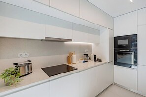 A modern kitchen with white cabinetry, a black countertop, a Bosch toaster, and a coffee maker. - Sal D’Ouro Atlantic Living | Gym & Garage (Vila Nova de Gaia)
