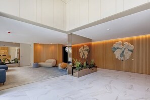 A spacious lobby with a high ceiling, a reception desk, seating area, and decorative wall panels. - Sal D’Ouro Atlantic Living | Gym & Garage (Vila Nova de Gaia)