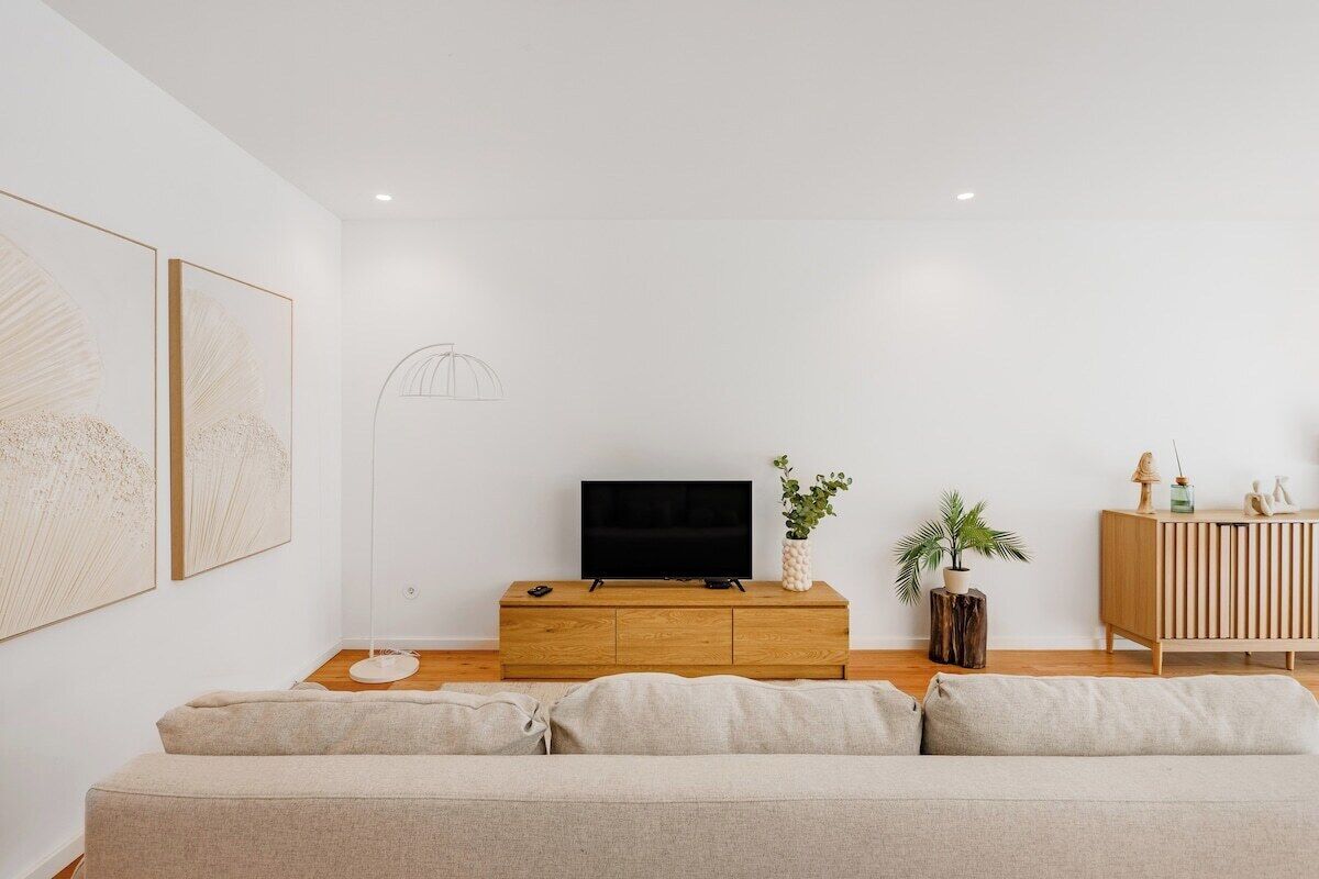 En minimalistisk stue med et tv-skab i træ, en sofa og et skab.