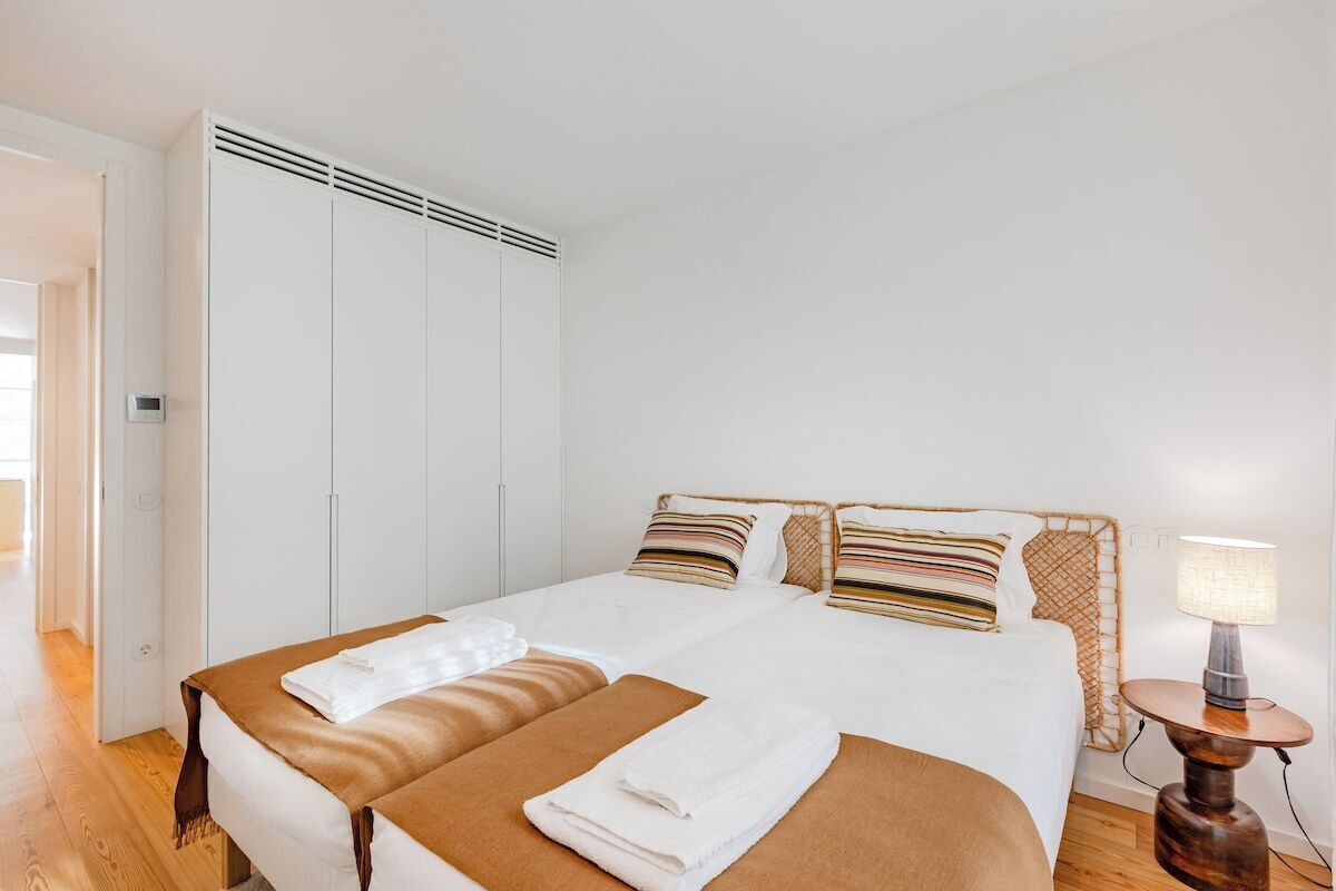 A hotel room with a bed, a bedside table with a lamp, and a wardrobe.