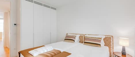 A hotel room with a bed, a bedside table with a lamp, and a wardrobe.