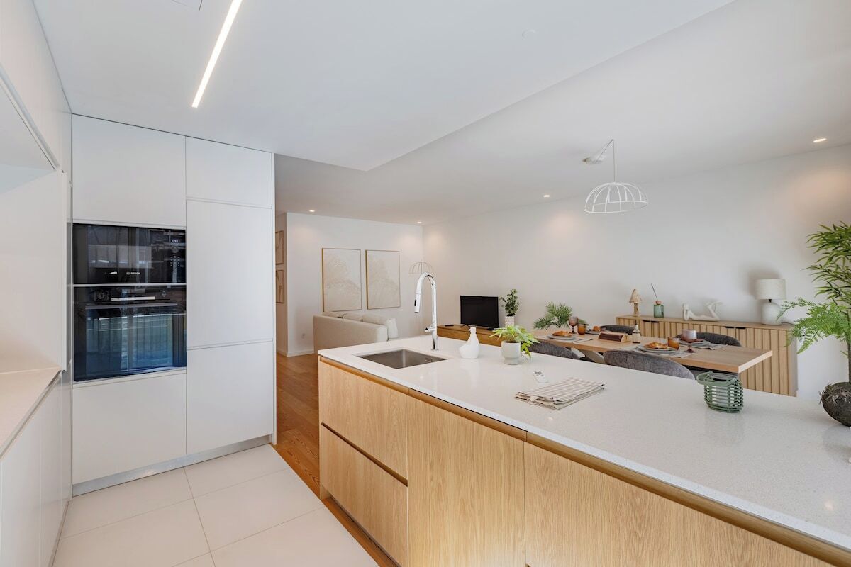 Une cuisine moderne dotée d’un îlot central, d’un four encastré et d’un coin repas avec une table et des chaises.