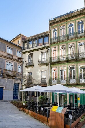 A courtyard with outdoor seating, a signboard, and a building with multiple balconies and windows. - Loft 77 | Porto Historic Centre (Porto)