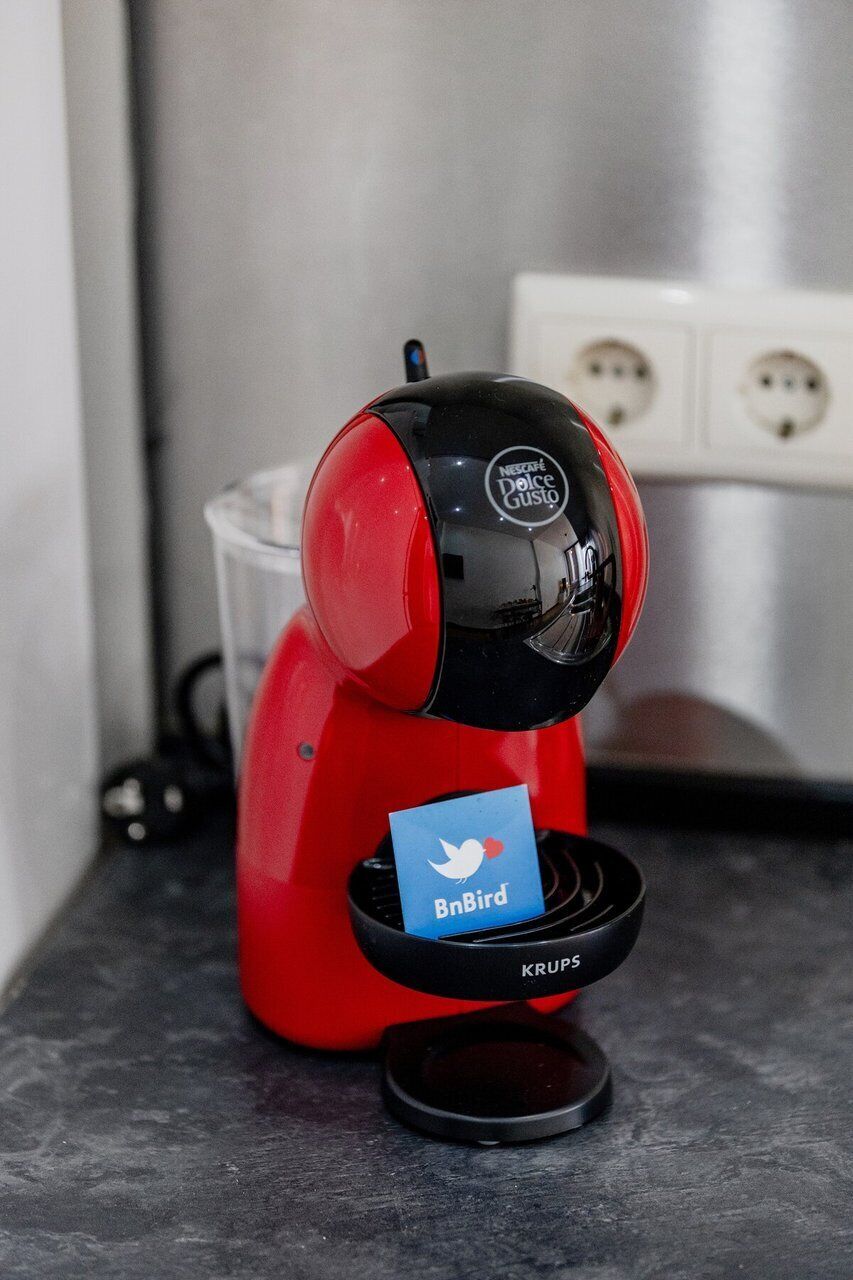 Eine rote Kaffeemaschine mit schwarzer Oberseite, eine blaue Karte eingelegt, und ein Etikett der Marke Krups.