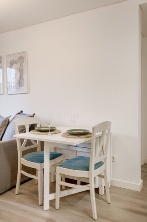 A dining area with a white table, two chairs with blue cushions, and two wine glasses. - Duque Central Stay | Walk to Rossio & Chiado (Lisbon)