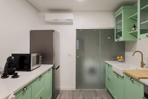 A compact kitchen with a microwave, coffee maker, and a glass door leading to a bathroom. - Duque Central Stay | Walk to Rossio & Chiado (Lisbon)