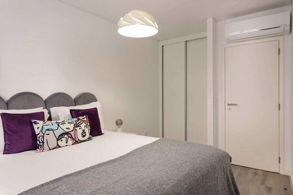 Un dormitorio con una cama, una puerta blanca y una lámpara en el techo.