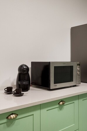 A kitchenette with a microwave, a coffee maker, and two cups on a white countertop. - Duque Central Stay | Walk to Rossio & Chiado (Lisbon)