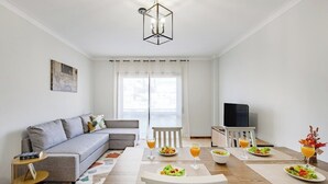 A modern living room with a sofa, dining table, and TV. - Gaia Comfort Living | Balcony & Metro (Vila Nova de Gaia)