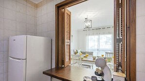 A kitchen with a white refrigerator, a coffee maker, and a tray with a mug and a box labeled 'COFFEE'. - Gaia Comfort Living | Balcony & Metro (Vila Nova de Gaia)