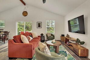 Una sala de estar con sofá, sillones, una mesa de centro, televisor y un comedor con sillas y mesa.