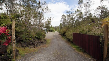 Un chemin de gravier mène à un bâtiment qui est bordé d’une clôture en bois d’un côté.