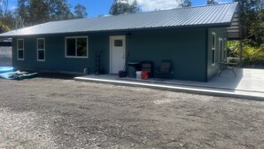 A small, single-story building with a metal roof, a front door, and a small porch area. - Charming 3-bedroom house in Volcano w/laundry & AC, perfect for your getaway! (Volcano)