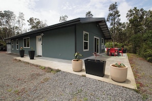 A modern two-story house with a flat roof, large windows, and a covered patio area with outdoor furniture.