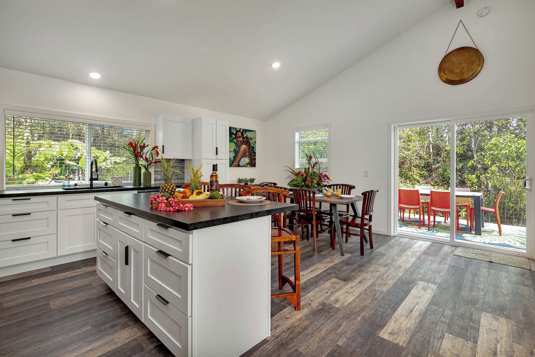 A modern kitchen with white cabinets, a large island, and a dining area with wooden chairs and a table.