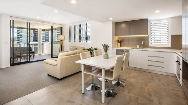 Un appartement moderne comprenant un coin repas, un canapé, une cuisine et un balcon.