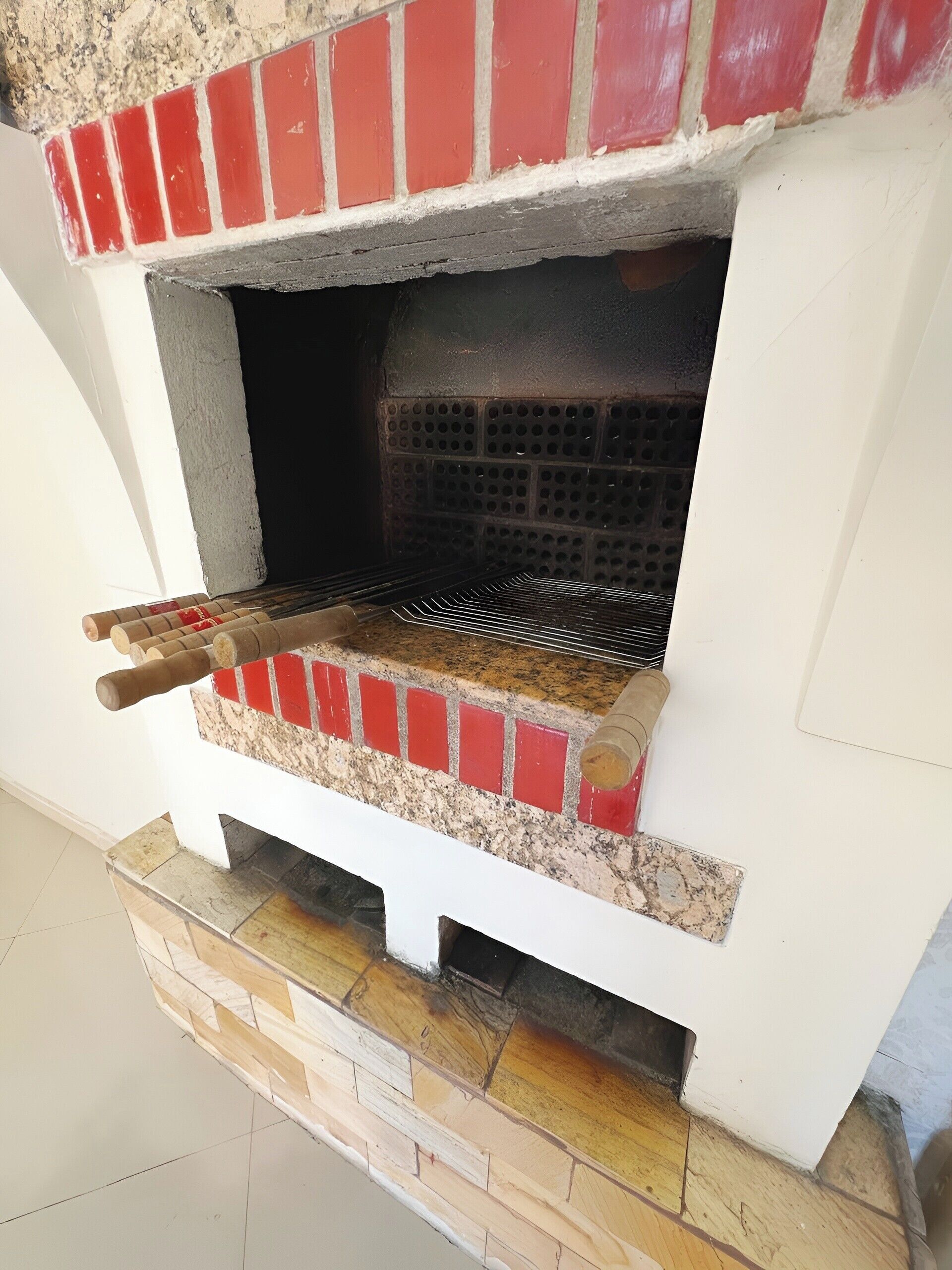 A brick-built outdoor oven with a metal rack and a chimney.