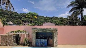 A swimming pool with a stone archway, a bar area, and a view of a hillside with greenery. - Casa com Piscina em Cabeçudas , 80 metros da Praia (Itajaí)