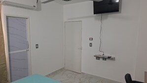 A room with a bed, a TV mounted on the wall, a door, and a small shelf with items. - Comfortable room with separate entrance (Barrancabermeja)