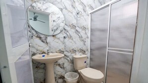 A bathroom with a marble backsplash, a sink, a toilet, and a shower enclosure. - Comfortable room with separate entrance (Barrancabermeja)