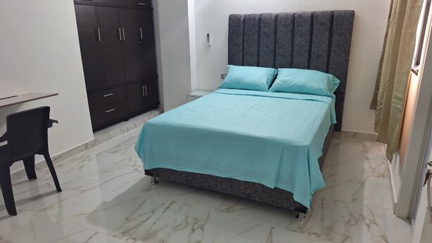 A bedroom with a bed, a desk, and a wardrobe. - Comfortable room with separate entrance (Barrancabermeja)