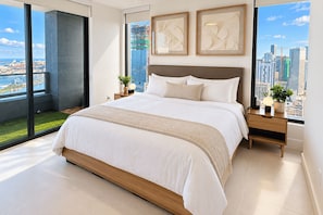 Ein modernes Schlafzimmer mit einem großen Bett, Blick auf die Stadt und Kunstwerken an den Wänden.