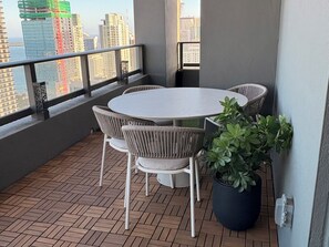 A balcony with a round table and chairs, a potted plant, and a view of city buildings. - High Floor 3-Bdr Apartment with Incredible Views, Pool & 24/7 Gym G4416 (Miami)